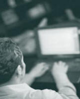 image of a man facing a computer screen and typing on it.